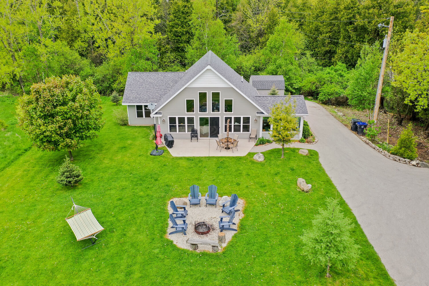 Aerial of Sawyer Harbor Retreat — cottage, lawn, fire pit circle, and hammock from above